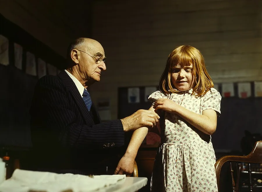 Dr. Schreiber of San Augustine giving a typhoid inoculation at a rural school, San Augustine County, Texas. April, 1943. Medium: transparency : color.